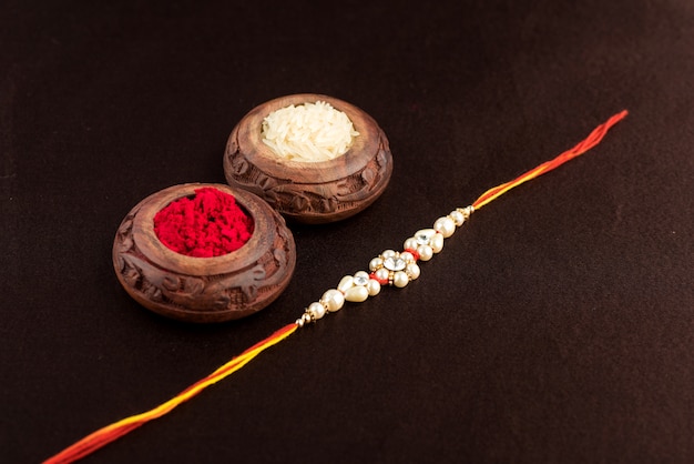 우아한 Rakhi, Rice Grains 및 Kumkum의 Raksha Bandhan. 형제와 자매 사이의 사랑의 상징 인 전통적인 인도 손목 밴드.