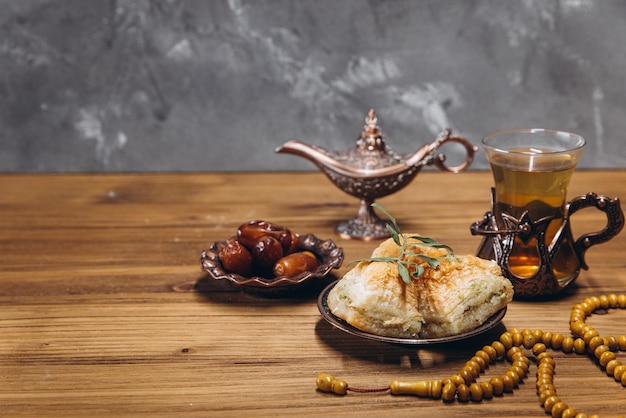 Концепция рамадана: чашка чая, тарелка со сладкими финиками и пространство для копирования пахлавы
