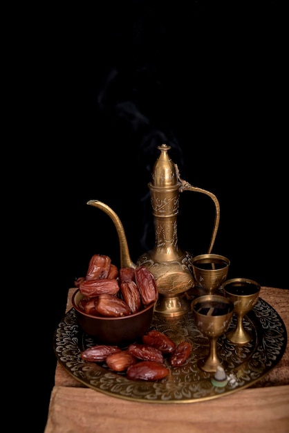 Photo ramadan concept dates closeup in the foreground ramadan lantern on a wooden table textured black wall background