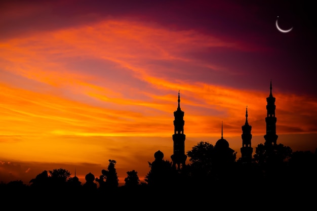 Ramadan Eid aifitrNew jaar Muharram islamitische religie symbolen met moskeeën koepel silhouet op donkere gouden schemering hemel in de nacht met wassende maan op zonsondergang arabische eid aladhamubarak moslim concept