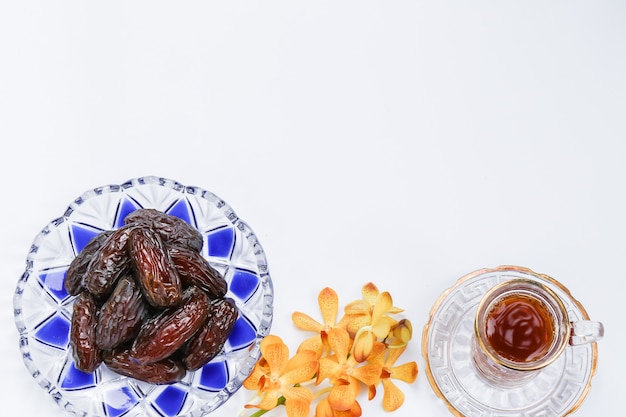 Foto ispirazione ramadan che mostra palme da datteri in un piatto modello islamico con fiori di orchidea e una tazza di tè