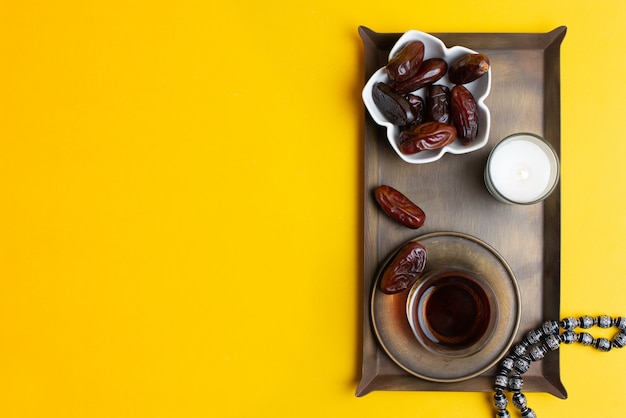 Ramadan Kareem Festival, close up of dates at bowl with rosary and cup of black tea 