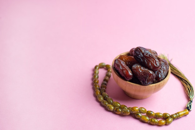 Ramadan Kareem Festival, Dates at bowl with rosary on pink background