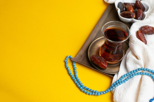 Photo ramadan kareem festival, dates on wooden bowl with cup of black tea and rosary