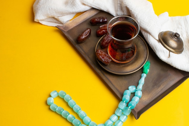 Ramadan Kareem Festival, Dates on wooden bowl with cup of black tea and rosary