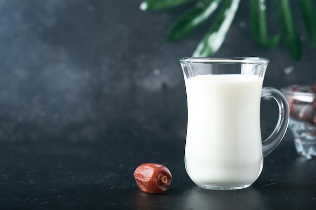 Ramadan Kareem food and drinks Plate of dates glass of milk and date palm branch on black background Righteous Muslim Lifestyle Vegetarian food Selective focus