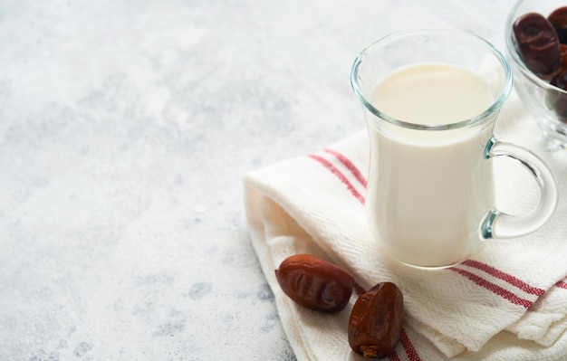 ラマダンカリームの食べ物と飲み物明るい灰色の背景にミルクとナツメヤシの枝の日付のプレートテキストのための正しいイスラム教徒のライフスタイルの場所選択的な焦点