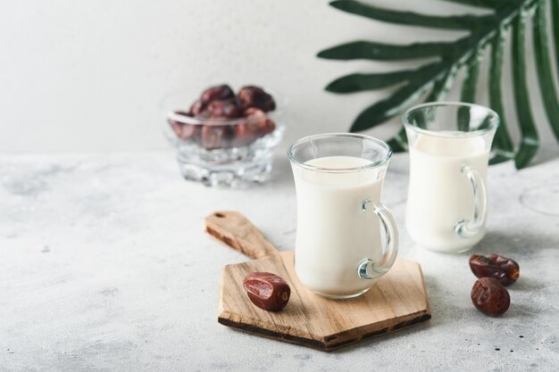 Ramadan Kareem food and drinks Plate of dates glass of milk and date palm branch on light grey background Righteous Muslim Lifestyle Place for text Selective focus