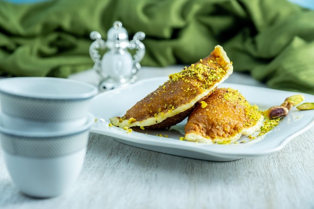 Ramadan sweets qatayef with white background and arabian coffee cups