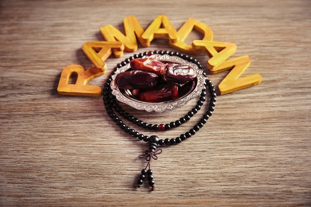 Ramadan word with wooden letters rosary and dry dates on table