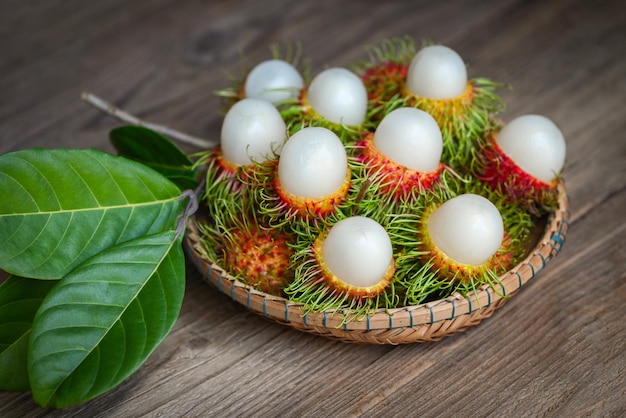 Rambutan raccolto di frutta dal giardino rambutan albero fresco e maturo rambutan dolce frutta tropicale rambutan pelato con foglia sul cesto di legno