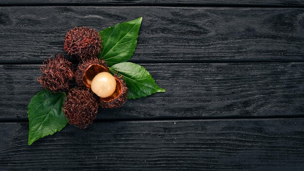 Rambutan Tropical Fruits On a wooden background Top view Copy space