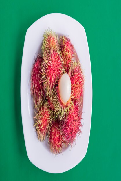 The rambutans  are in a plate on green paper background