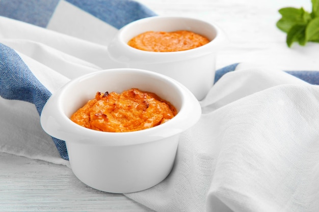 Ramekins with tasty carrot souffle on wooden table