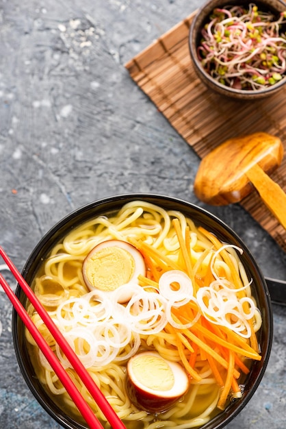 Zuppa di ramen con uovo marinato servita con tagliatelle e verdure fresche