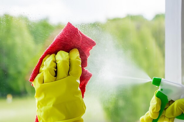 Ramen wassen. Jonge vrouw in gele rubberen handschoenen veegt het glas af. Huishoudelijk werkconcept.