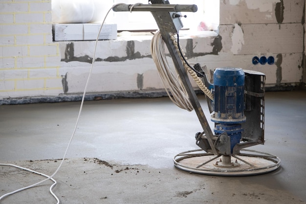 Ramming and grinding of semidry floor screed by a machine with a rotating disk for leveling Construction of a concrete floor in the house a master with special equipment