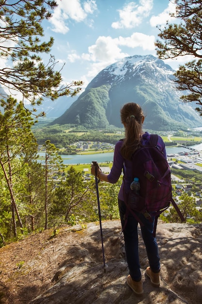 Rampestreken. girl hiker with a backpack and trekking pole standing and looking on Romsdalsfjorden and Andalsnes, Norway