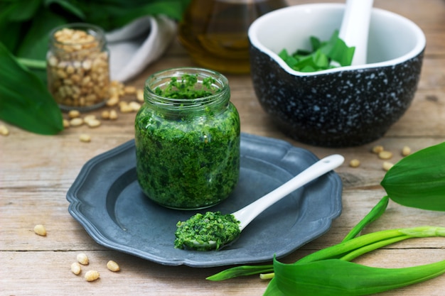 Photo ramson pesto and ingredients for cooking it on a wooden table. rustic style.