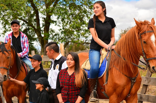 Rancho Fenix, Latacunga, Cotopaxi, Ecuador 12 augustus 2016. Verschillende mensen staan naast 2 paarden met twee ruiters