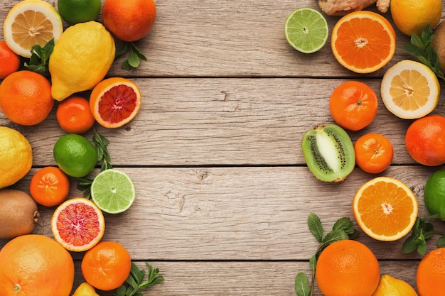 Rand van diverse citrusvruchten op rustieke houten achtergrond, kopieer ruimte. Bovenaanzicht op sinaasappelen, citroenen, mandarijnen en ander exotisch fruit, plat gelegd