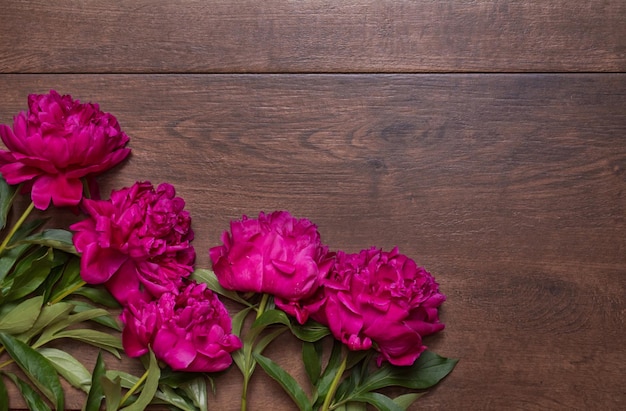 Rand van pioenrozen op een houten ondergrond Bloemmotief Roze en paarse lentebloemen