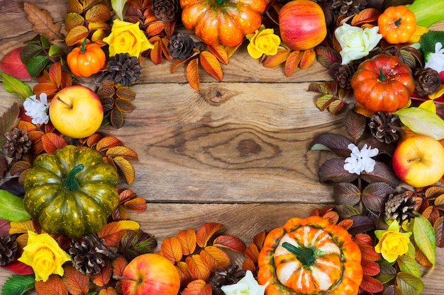 Rand van pompoenen, appels, dennenappels, herfstbladeren, gele rozen