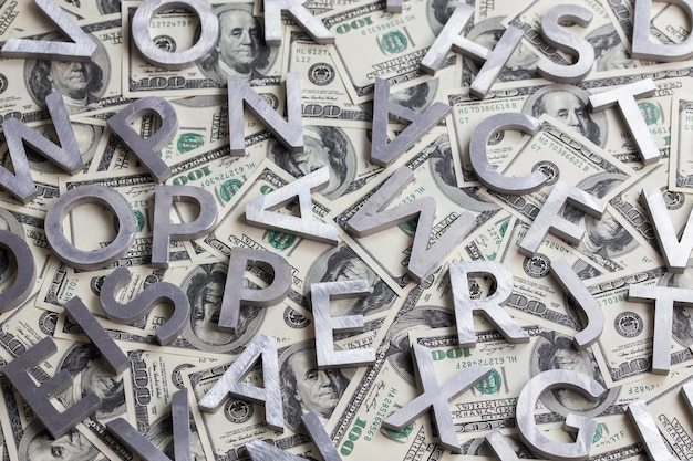 Случайные металлические буквы на фоне доллара США