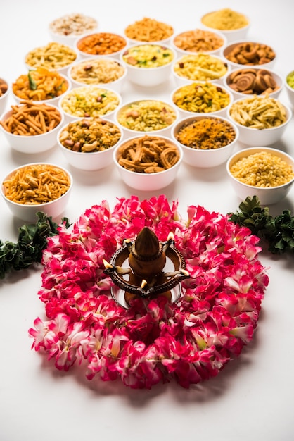 Photo rangoli of farsan or snacks in bowls for diwali with diya