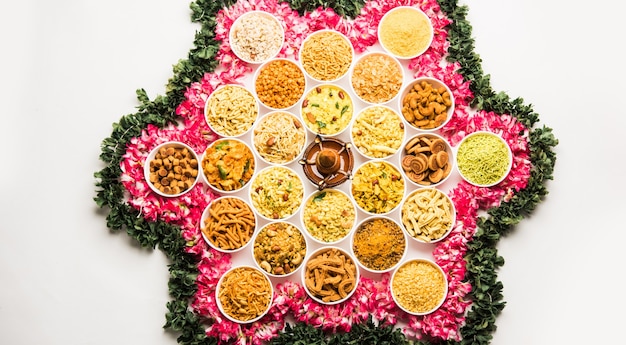 Photo rangoli of farsan or snacks in bowls for diwali with diya