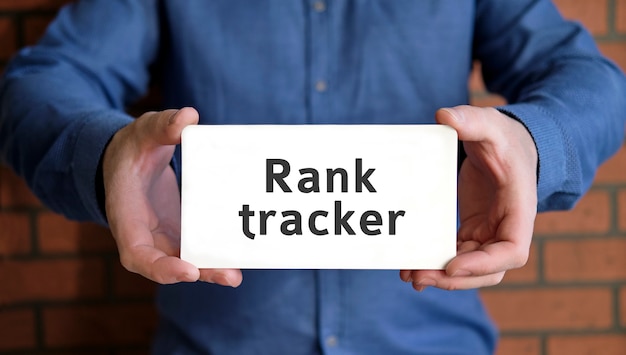 Rank tracker - seo concept проверка ранга сайта в руках молодого человека в синей рубашке