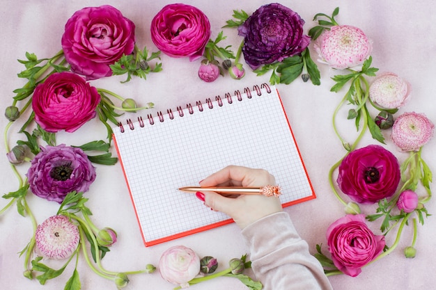Photo ranunculus, woman's hand, pen and blank notebook
