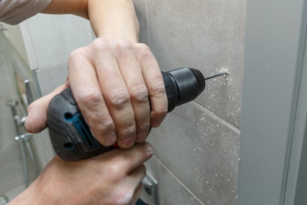 Photo rapairman drilling ceramic tile on a wall