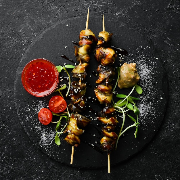 Rapana skewers with vegetables on a black stone plate Restaurant food Seafood Rustic style Flat Lay