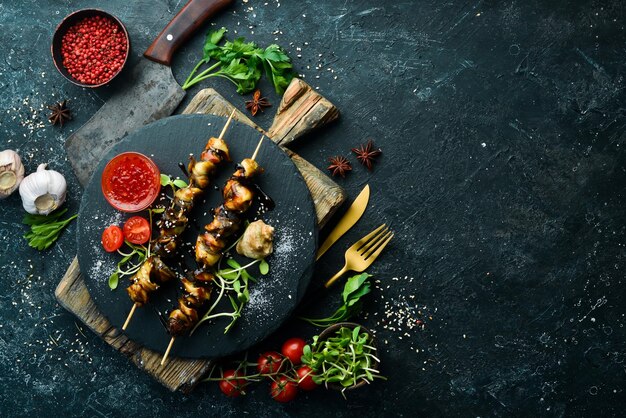 Rapana skewers with vegetables on a black stone plate\
restaurant food seafood rustic style flat lay