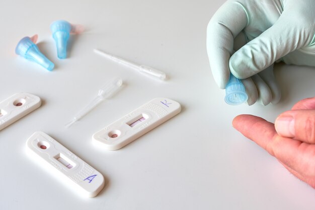 Rapid COVID-19 test for detection of specific antibodies IgM and IgG to novel corona virus SARS-CoV-2 causing Covid-19. Medic or doctor in protective gloves is about to pick patient finger.