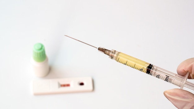 Rapid test kit for the coronary19 virus a vaccine contained in a syringe on a white background