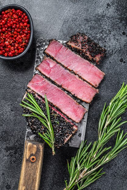 Rare ahi tuna steak slices on a meat cleaver. black background.\
top view.