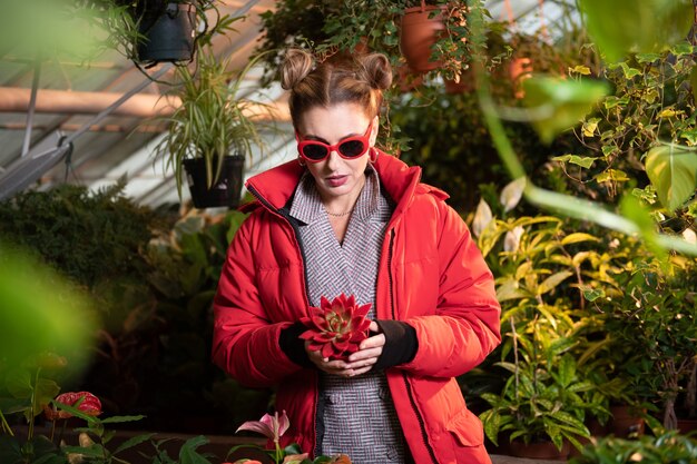 Rare flower. Beautiful pretty woman holding a beautiful red flower while being in the greenhouse