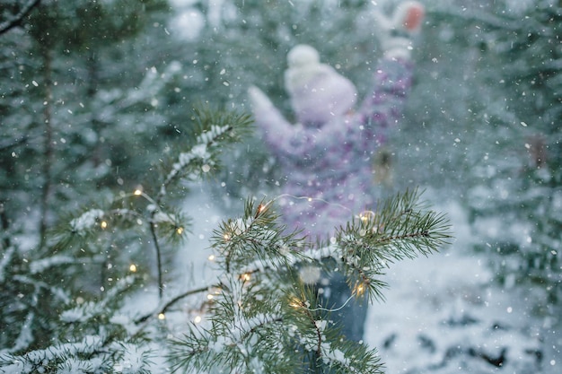 冬のワンダーランドの裏天気で雪に覆われた森を歩いている家族の間に女の子の珍しいビュー