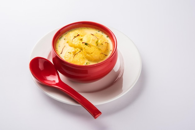 Ras malai 또는 rossomalai는 인도 벵골의 디저트입니다. 사프란이나 케사르&피스타치오 토핑을 얹은 크러스트가 없는 진한 치즈케이크입니다. 나무 또는 화려한 배경 위에 그릇에 제공