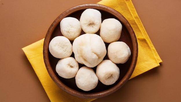 Photo rasgulla or rosogulla an indian sweet made from khoya soft and spongy in earthen bowl over yell