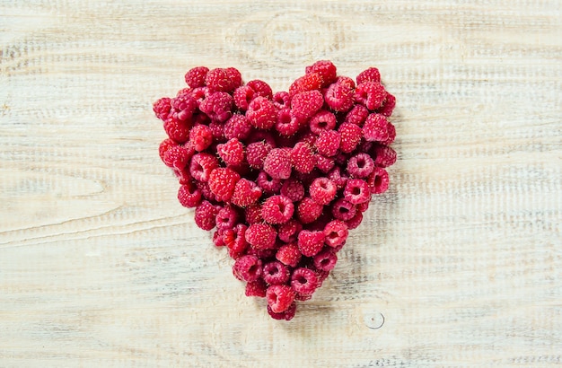 Raspberries are in the hands of a child in the form of a heart.