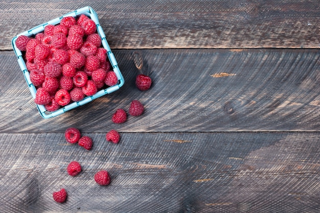 Raspberries in a basket on old wooden background