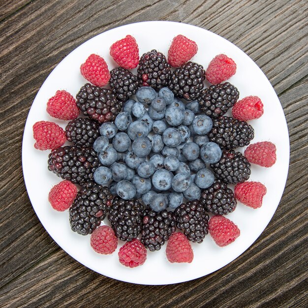 Raspberries, blueberries and blackberries on a white plate