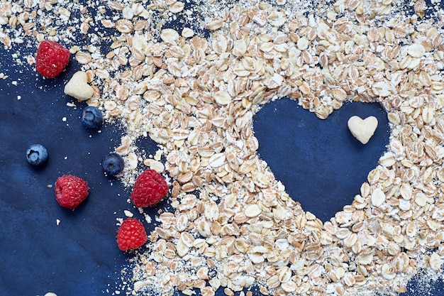 Raspberries and blueberries on blue background. Cereals.