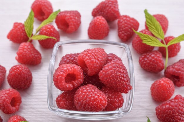 Raspberries in a bowl on a wooden textured background