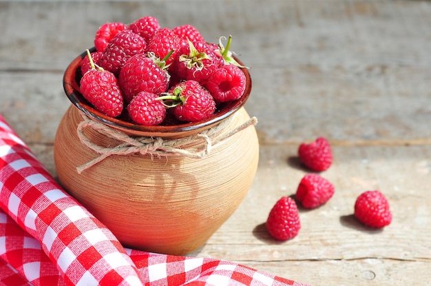 raspberries in clay pot on wooden background