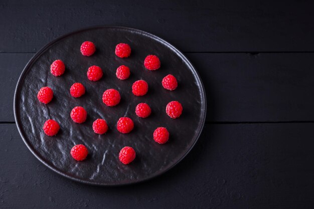 Raspberries on dark background Red raspberry on black plate Red berries on wooden boards