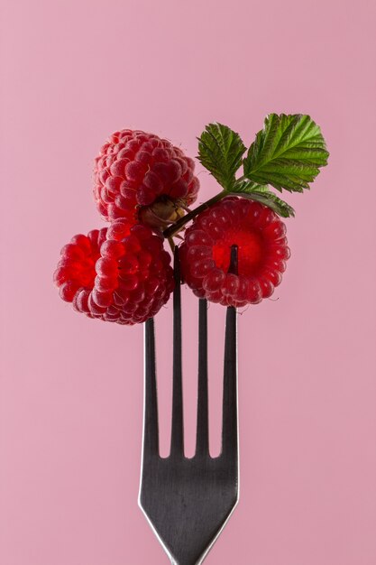 Raspberries on fork against pink . Healthy eating concept